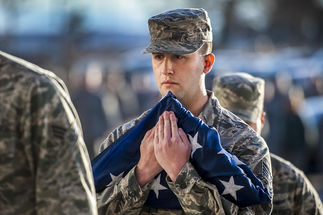 An airman assigned to the 50th Space Wing holds a flag as he participates in a monthly wing retreat ceremony at Schriever Air Force Base near Colorado Springs, Colo., Jan. 30, 2017. Air Force photo by Dennis Rogers