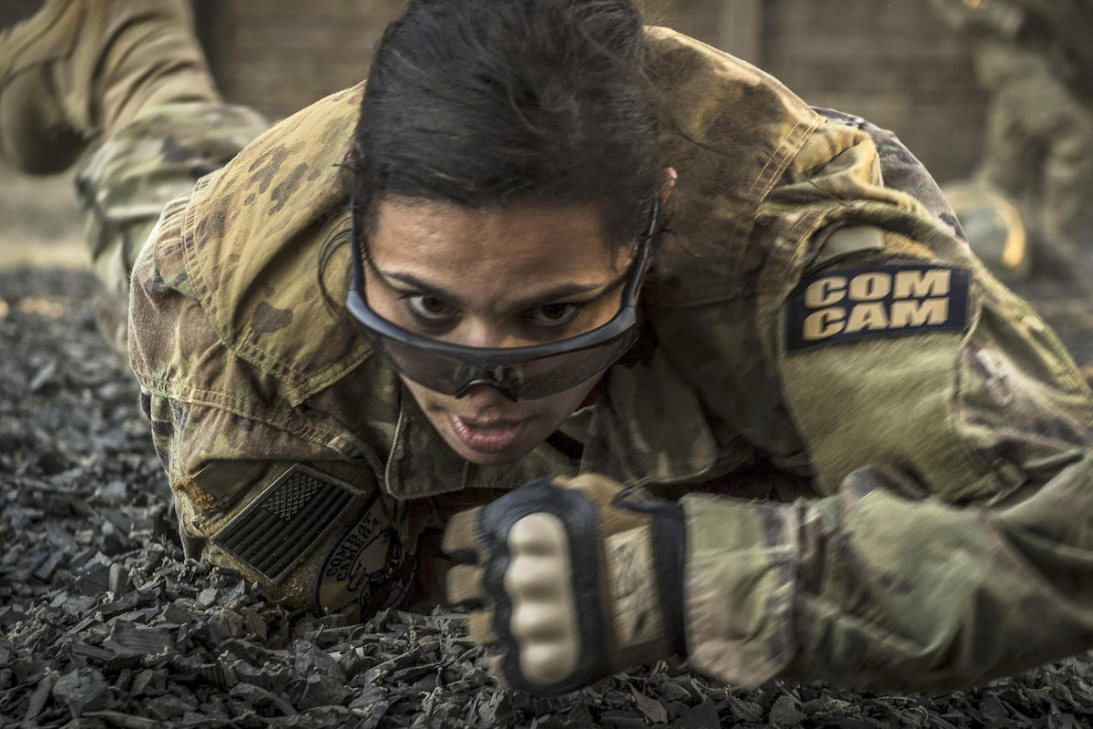 An airman low crawls while navigating an obstacle course.