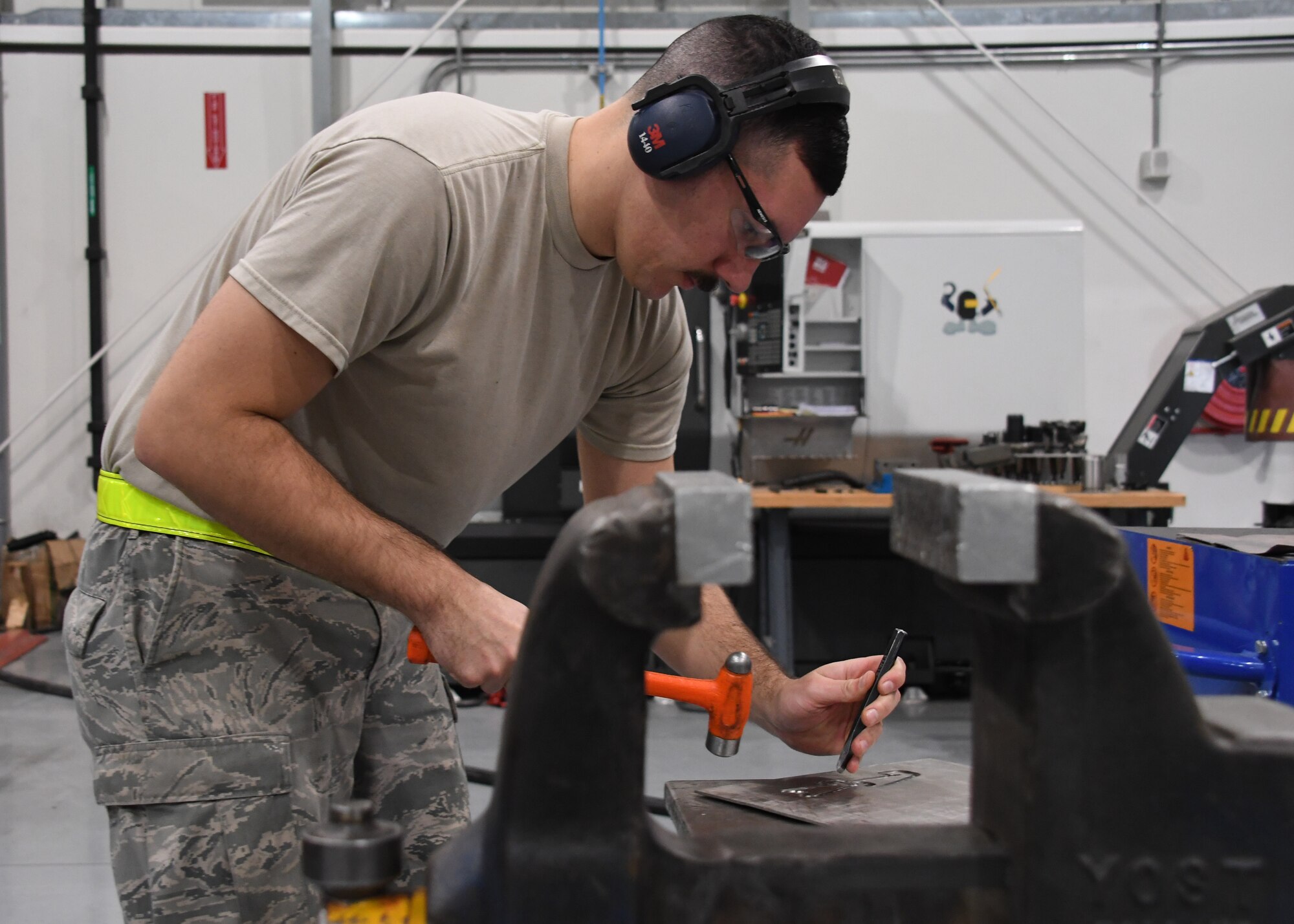 U.S. Air Force Staff Sgt. Eric Kerr, a fabrication flight metals technician with the 379th Expeditionary Maintenance Squadron, uses a chisel and mallet to punch out a part at Al Udeid Air Base, Qatar, Feb. 2, 2017. Kerr was working on a spring-tensioning tool commissioned by the U.S. Navy. (U.S. Air Force photo by Senior Airman Miles Wilson)