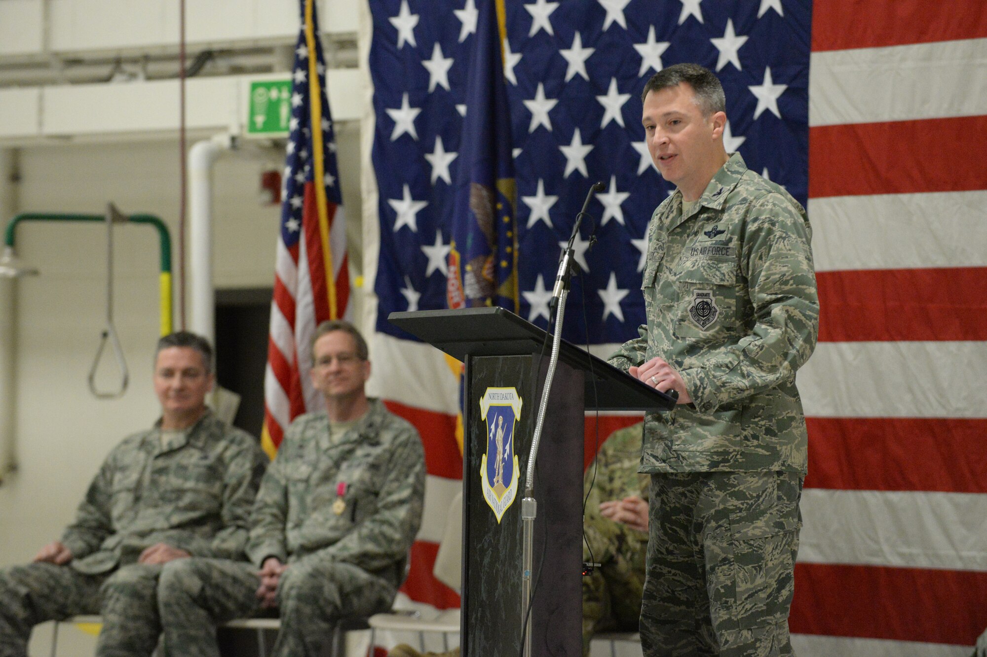 Col. Thomas “Britt” Hatley addresses the 119th Wing unit members standing in formation for the first time as their commander during a change of command ceremony at the North Dakota Air National Guard Base, Fargo, N.D., Feb. 4, 2017. Hatley is replacing out-going 119th Wing commander Col. Kent Olson, seated second from left, who has been the 119th Wing commander since March 14, 2013. (U.S. Air National Guard photo by Senior Master Sgt. David H. Lipp/Released)