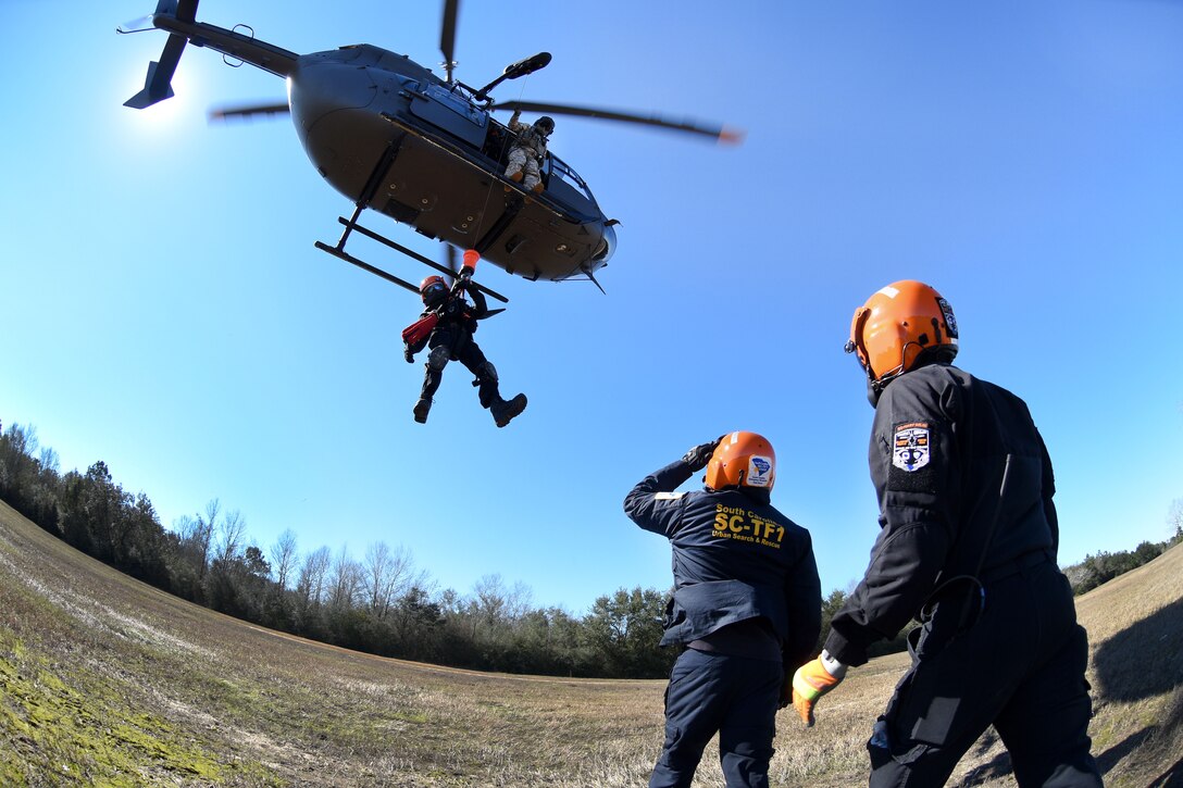 An Army National Guard crew chief guides the hoist line for an emergency first responder being lowered during the first phases of Patriot South Exercise 2017, at the Gulfport and Port Bienville Industrial Complex, Mississippi, Jan. 29, 2017. Army National Guard photo by Staff Sgt. Roberto Di Giovine 