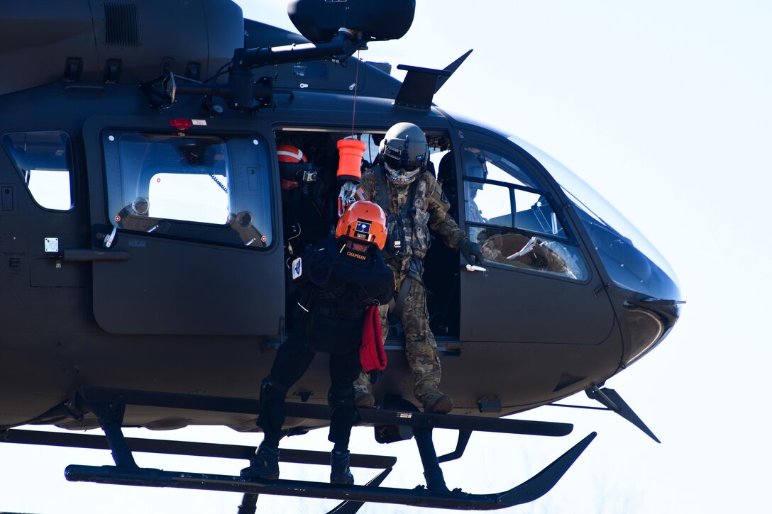 An Army National Guard crew chief assists an emergency first responder before being lowered from a LUH-72A Lakota helicopter during the first phases of Patriot South Exercise 2017, at the Gulfport and Port Bienville Industrial Complex, Mississippi, Jan. 29, 2017. Army National Guard photo by Staff Sgt. Roberto Di Giovine