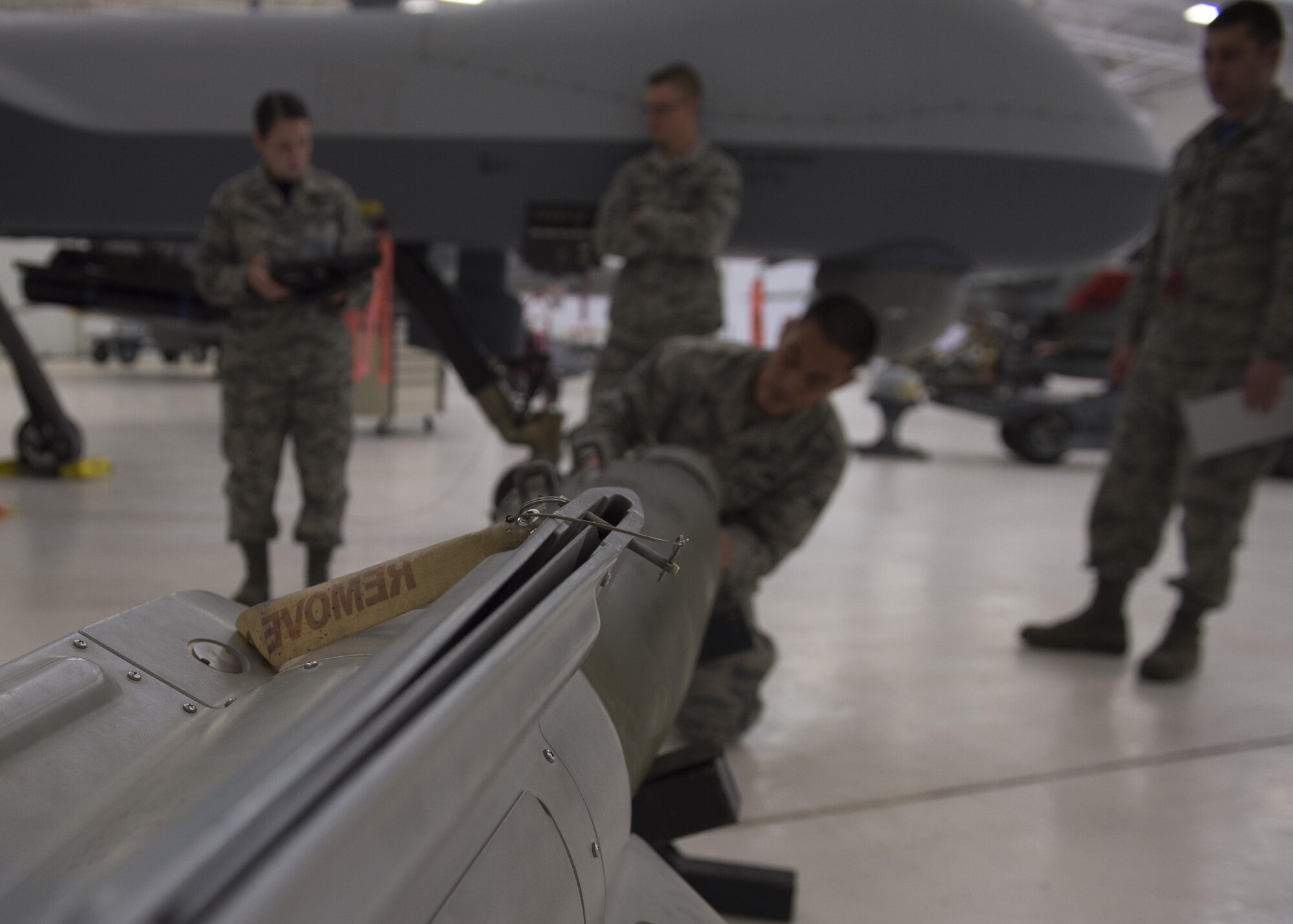 Members of the 49th Wing Maintenance Group inspect an inert munition before loading it onto an MQ-9 Reaper during a quarterly load crew competition at Holloman Air Force Base, N.M., Jan. 20, 2016. The weapons load crews for German Air Force Tornado, F-16 Fighting Falcon and MQ-9 Reaper competed against each other to load weapons the most efficiently and with the least amount of procedural errors. Points for the competition are awarded based on weapons loading, tool kit inspection and uniform inspection categories. (U.S. Air Force photo by Senior Airman Chase Cannon/ Released)