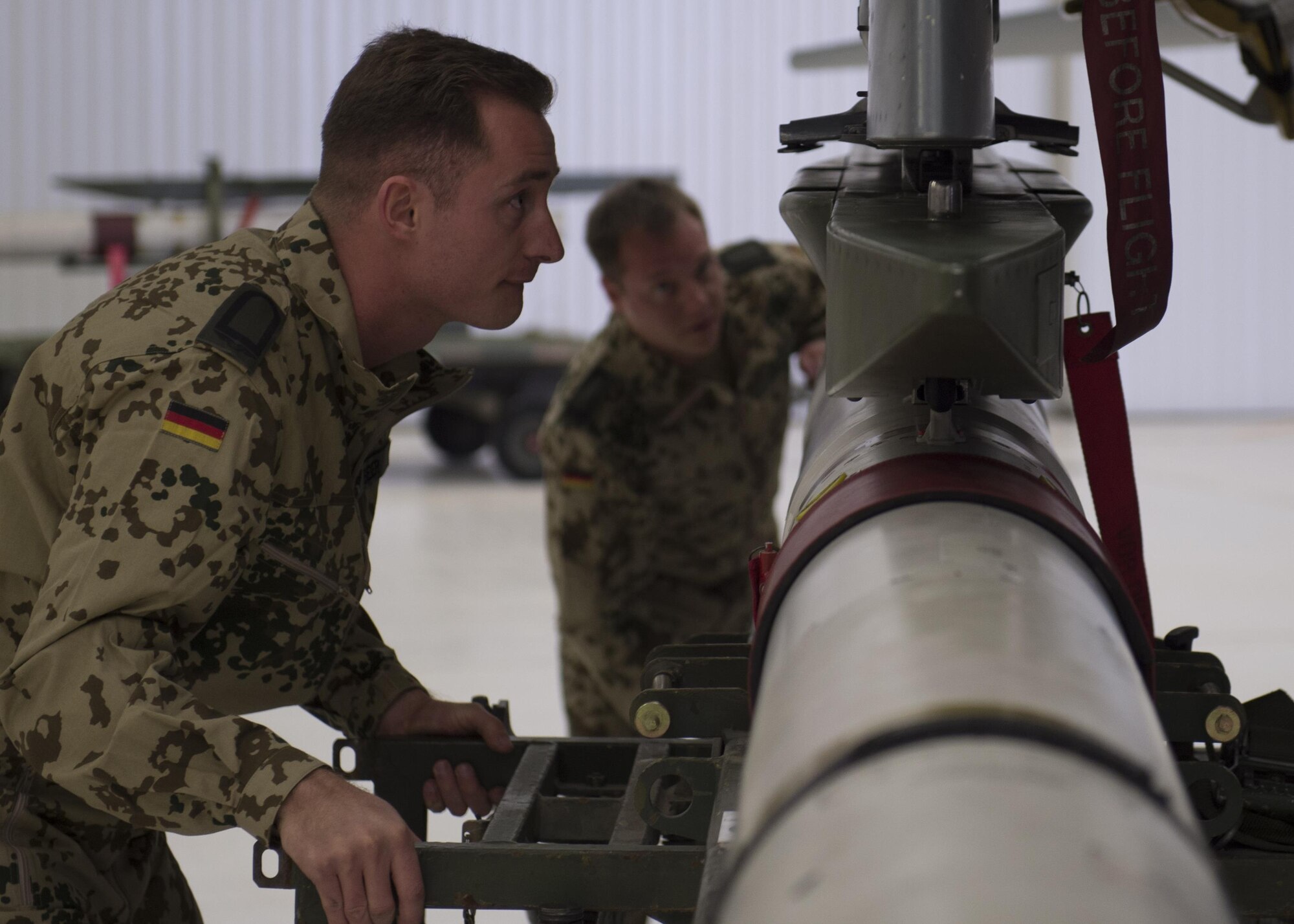 German Air Force Flying Training Center members load an inert munition onto a GAF Tornado during a quarterly load crew competition at Holloman Air Force Base, N.M., Jan. 20, 2016. The GAF competed for the last time in the load crew competition to have their skills evaluated alongside the MQ-9 Reaper, and the F-16 Fighting Falcon load crews. Points for the competition are awarded based on weapons loading, tool kit inspection and uniform inspection categories. (U.S. Air Force photo by Senior Airman Chase Cannon/ Released)