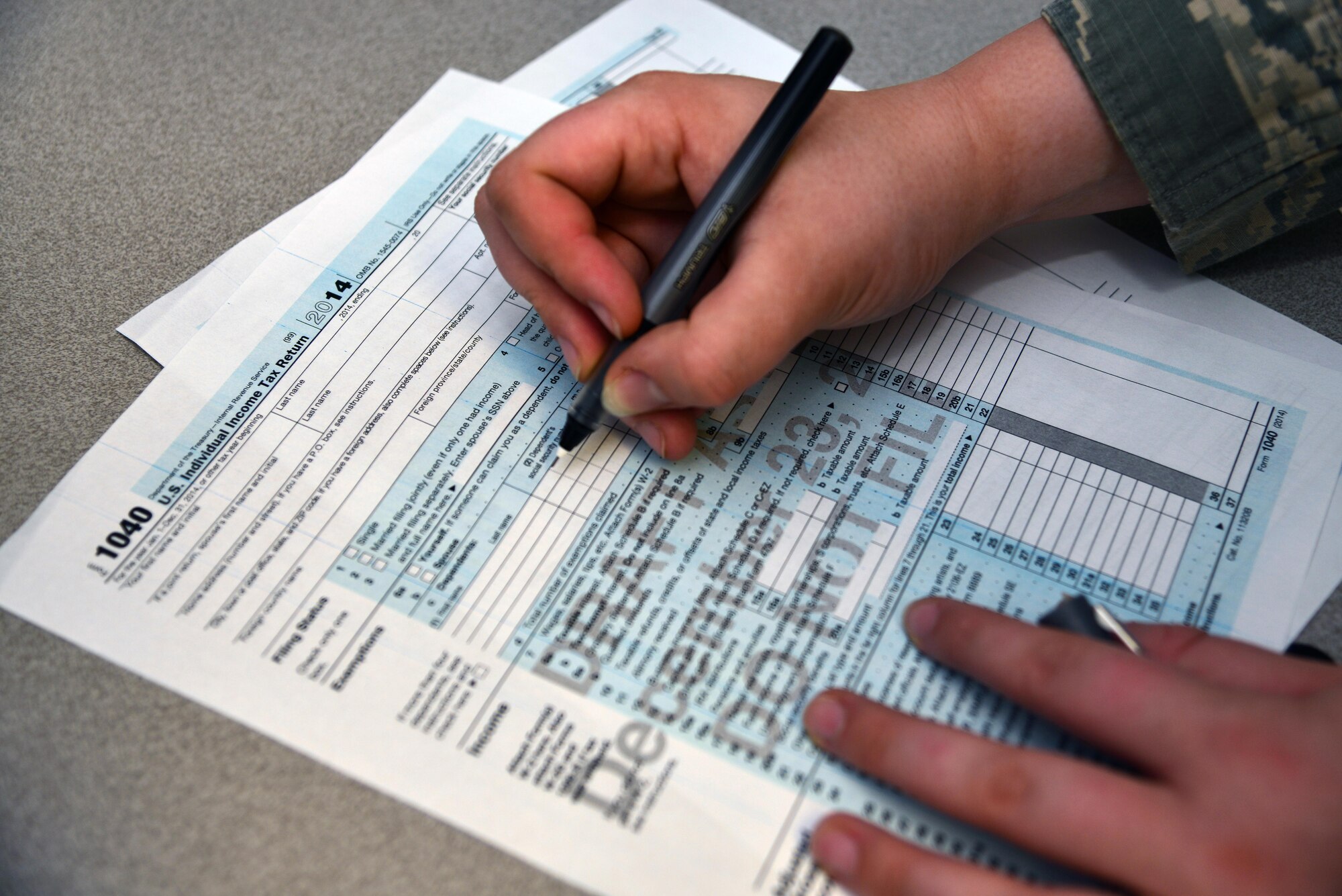 U.S. Air Force Senior Airman Holden Smith, 633rd Air Base Wing Judge Advocate paralegal, assists Senior Airman Terrence Eaton, logistics readiness squadron vehicle maintenance journeymen, in filling out a form at the Langley Air Force Base, Va., tax center Feb. 5, 2013. As in the past, tax assistance is being offered to members of the armed forces and their families.