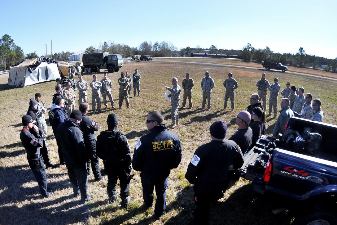 Army National Guard Chief Warrant Officer 4 Sean Reynolds, center, gives an after action review to soldiers, fire department and emergency medical services rescuers from the South Carolina Helicopter Aquatic Rescue Team, and the South Carolina Urban Search and Rescue Task Force 1, after participating in hoist training operations during the first phases of Patriot South Exercise 2017, at the Gulfport and Port Bienville Industrial Complex, Mississippi, Jan. 29, 2017. Army National Guard photo by Staff Sgt. Roberto Di Giovine