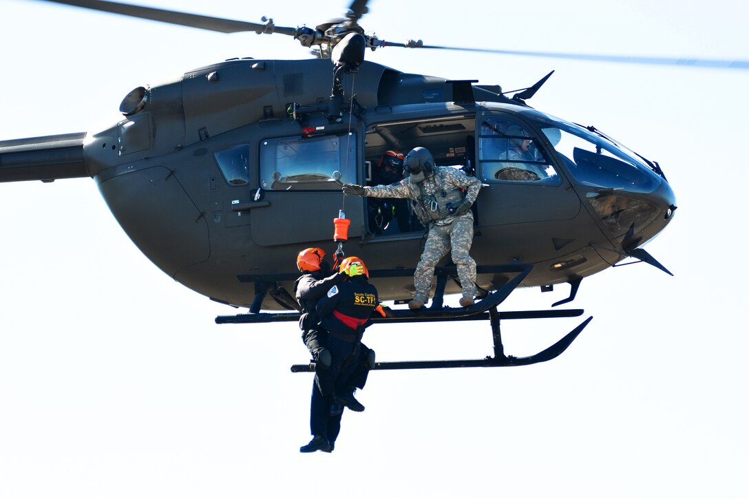 An Army National Guard crew chief assists two emergency first responders being hoisted up onto a LUH-72A Lakota helicopter during the first phases of Patriot South Exercise 2017, at the Gulfport and Port Bienville Industrial Complex, Mississippi, Jan. 29, 2017. Army National Guard photo by Staff Sgt. Roberto Di Giovine