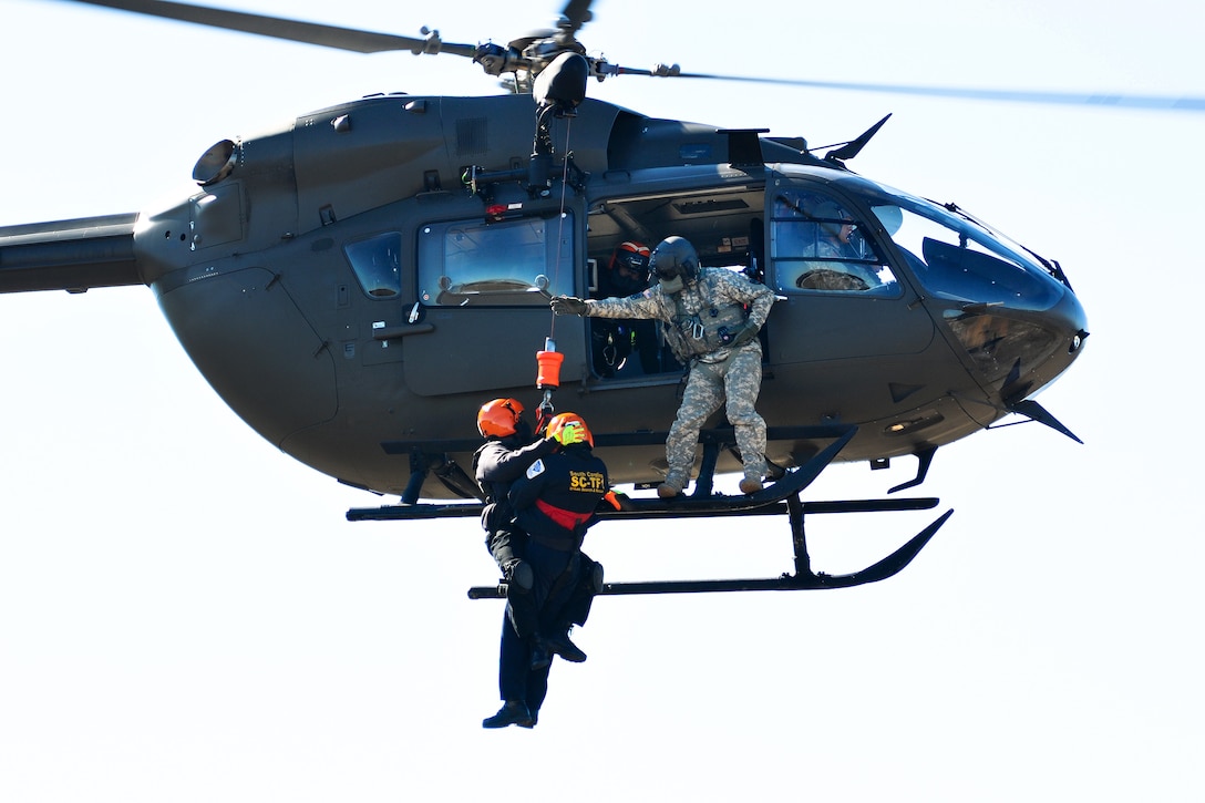 An Army National Guard crew chief assists two emergency first responders being hoisted up onto a LUH-72A Lakota helicopter during the first phases of Patriot South Exercise 2017, at the Gulfport and Port Bienville Industrial Complex, Mississippi, Jan. 29, 2017. Army National Guard photo by Staff Sgt. Roberto Di Giovine