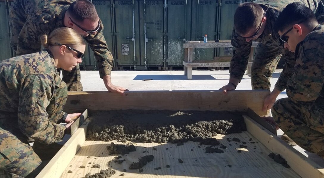 On January 30, 2017 Marines attached to Combat Engineer Officer course 2-17 (CEO 2-17) screed a concrete slab. During their period of instruction, CEO students learn how to plan for and execute concrete construction. Pictured from left to right:  Second Lieutenant Kerri Hands, First Lieutenant Andrew Wallace, and Second Lieutenants Chase Alexanian and Manuel Ramirez.
