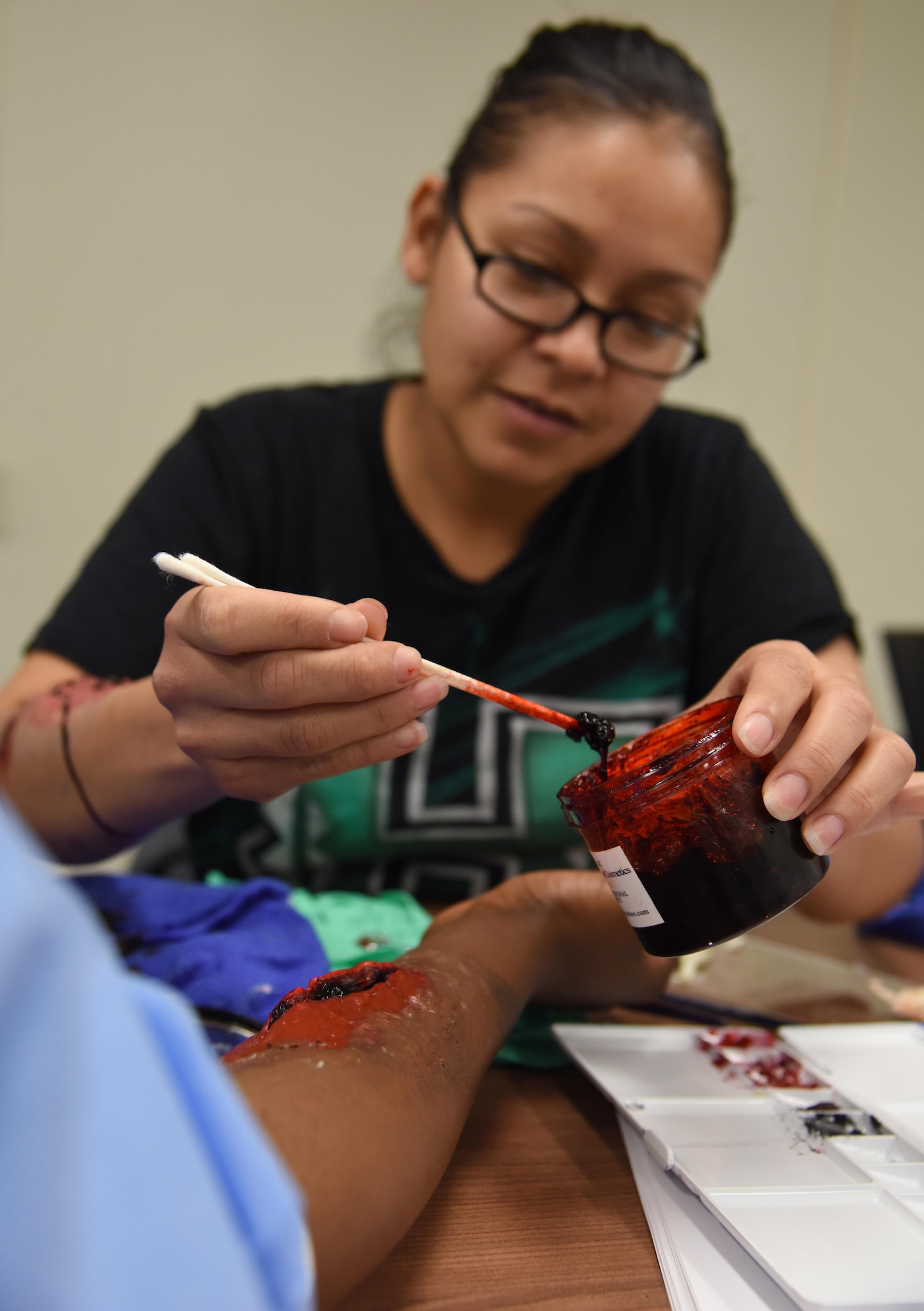 Tech. Sgt. Susana Luna, 334th Training Squadron instructor supervisor, applies moulage on a volunteer during a training session at Allee Hall Jan. 18, 2017, on Keesler Air Force Base, Miss. The session was held to teach volunteers how to apply moulage on exercise “casualties” to provide emergency responders with a more realistic training experience. (U.S. Air Force photo by Kemberly Groue)
