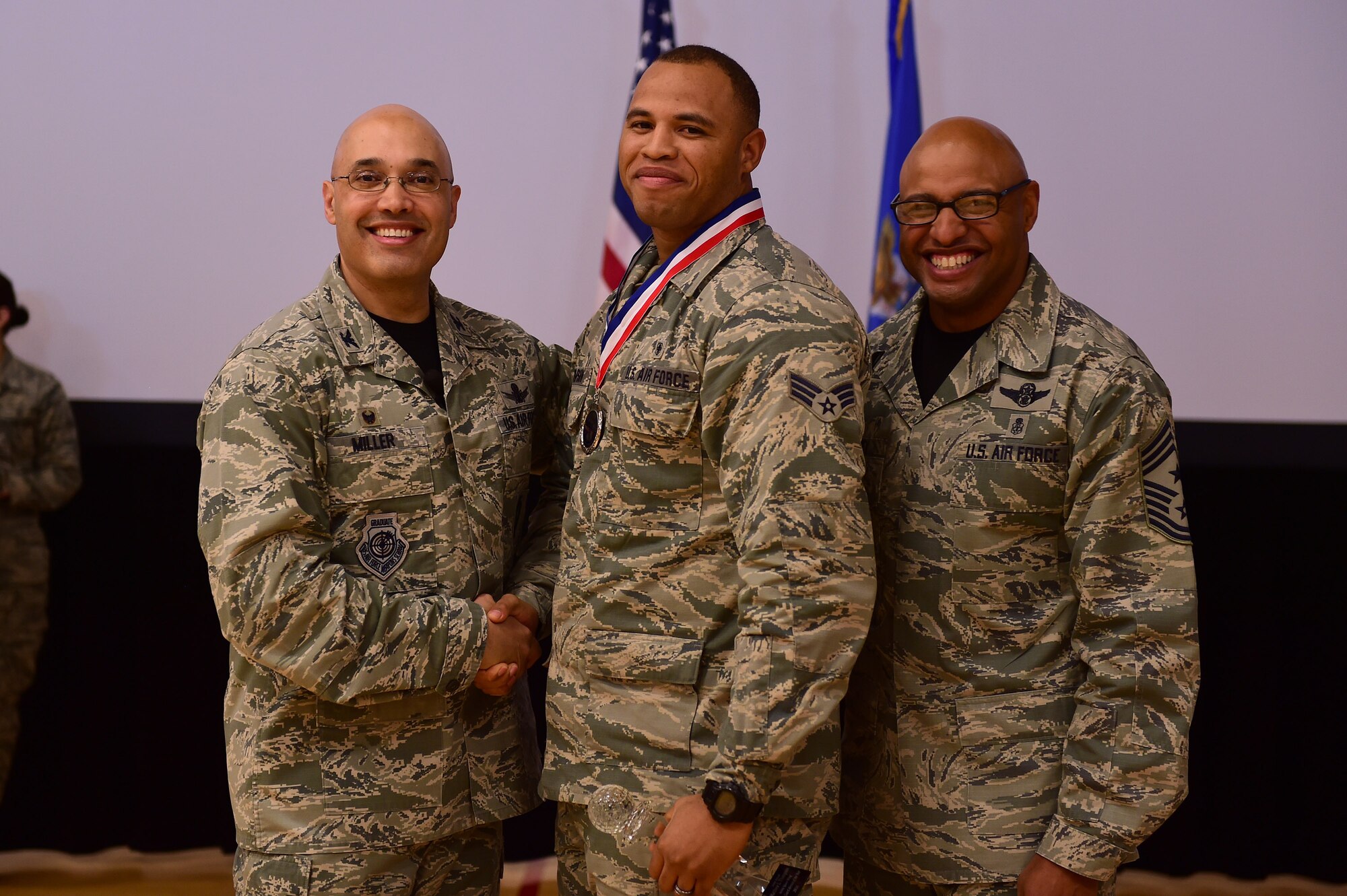 Senior Airman Matthew Thompson, Mile High Honor Guard Airman, center, receives the Honor Guard Airman of the Year Award, from Col. David Miller Jr., 460th Space Wing commander, and Chief Master Sgt. Rod Lindsey, 460th SW command chief, Feb. 3, 2017, at the annual awards on Buckley Air Force Base, Colo. The annual awards is a ceremony that recognizes the significant achievements, dedication and skill of the military and civilian members of the 460th SW. (U.S. Air Force photo by Airman Jacob Deatherage/Released)