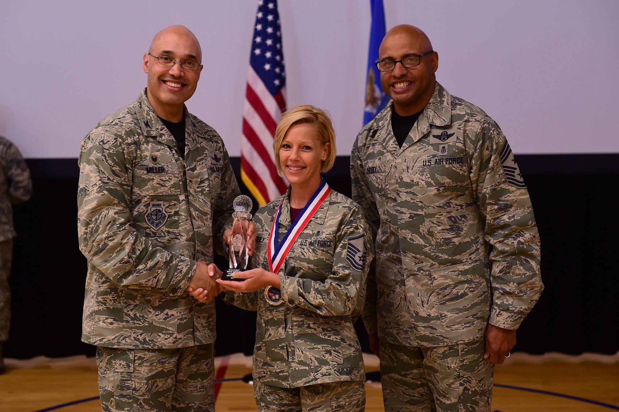 Master Sgt. Stacey Lindsey, 460th Medical Group, receives the Senior NCO of the Year Award, from Col. David Miller Jr., 460th Space Wing commander, and Chief Master Sgt. Rod Lindsey, 460th SW command chief, Feb. 3, 2017, at the annual awards on Buckley Air Force Base, Colo. The annual awards is a ceremony that recognizes the significant achievements, dedication and skill of the military and civilian members of the 460th SW. (U.S. Air Force photo by Airman Jacob Deatherage/Released)
