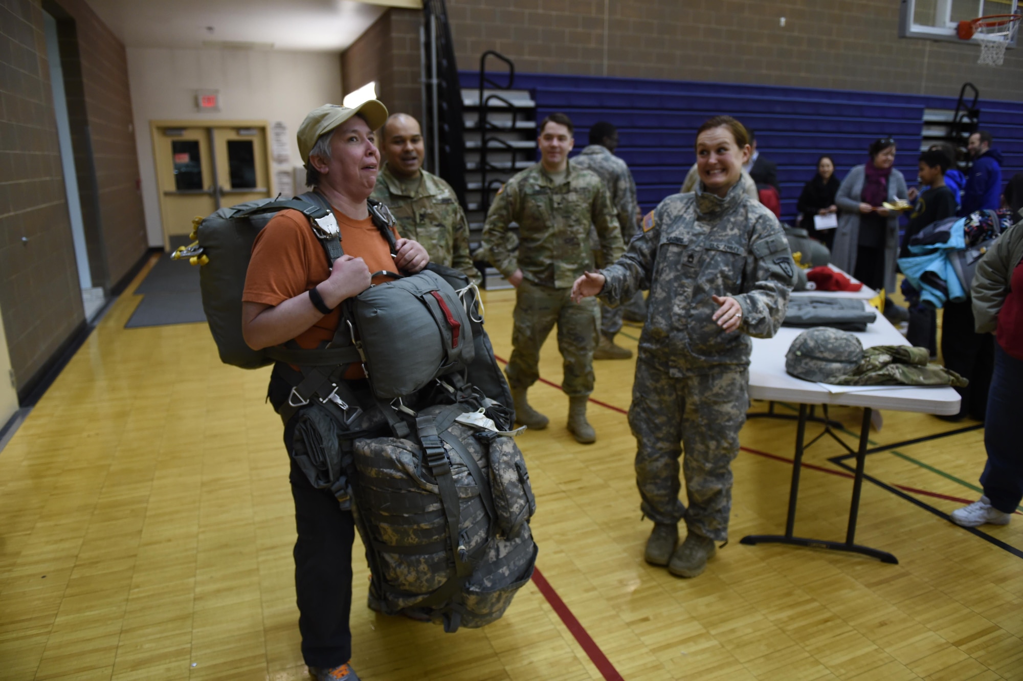 Jen Mickelson, Begich Middle School family school services support coordinator, attempts to jump in a T-11 parachute at Begich Middle School, Feb. 2, 2017. Headquarters and Headquarters Company, 4th Brigade Combat Team (Airborne), 25th Infantry Division Soldiers were one of many Science, Technology, Engineering, Art and Math presenters who interacted with about 300 students at the school's Career Fair. The fair is one of several annual events the unit's Soldiers support at the school as part of the Joint Base Elmendorf-Richardson School Partnership Program.