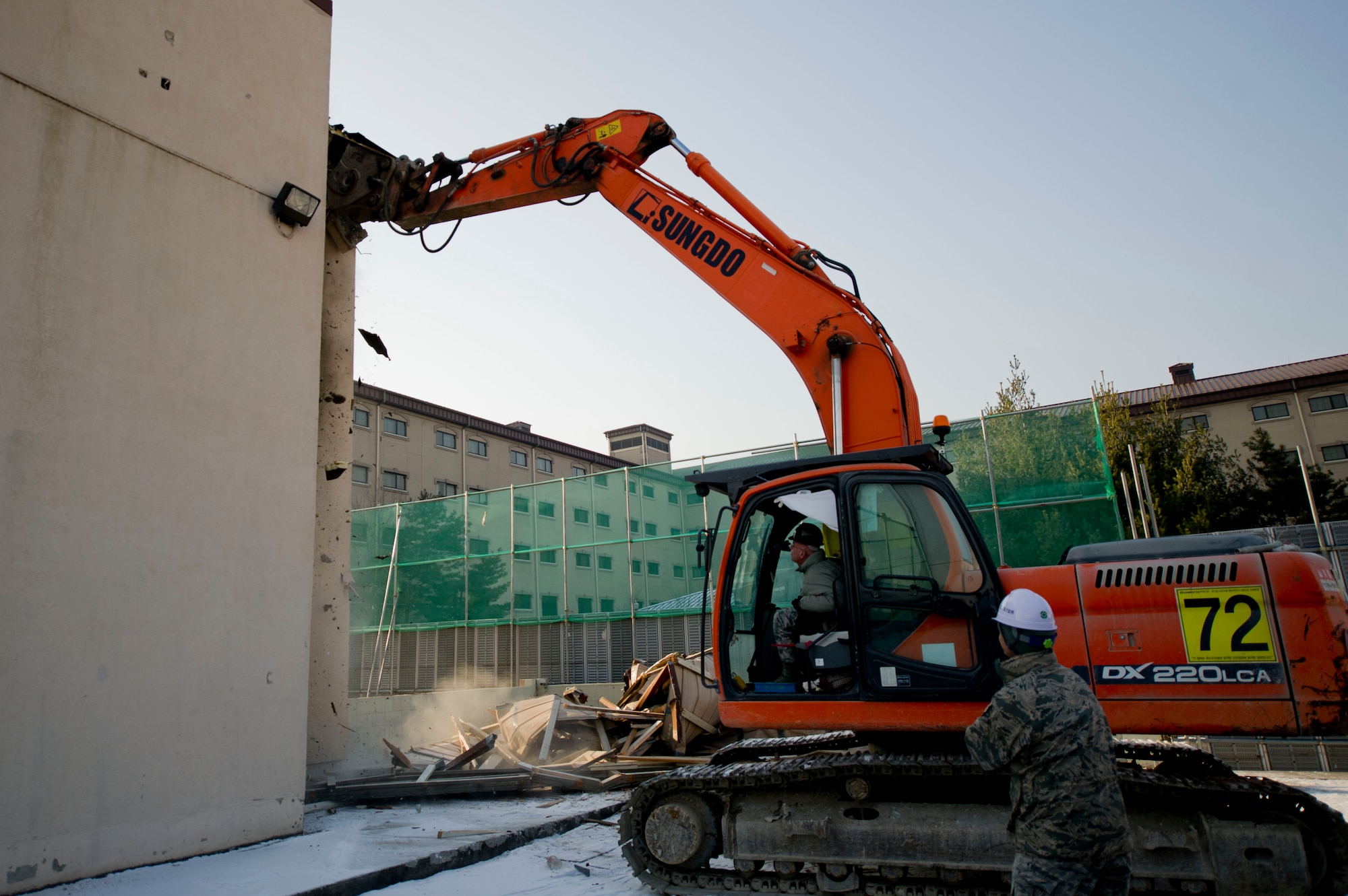 U.S. Air Force Chief Master Sgt. Alexander del Valle, 51st Fighter Wing command chief, uses an excavator to demolish part of an old dorm at Osan Air Base, Republic of Korea, Feb. 1, 2017. Some of the improvements to new dorms include architectural enhancements, electrical and plumbing upgrades and interior finishes. (U.S. Air Force photo by Staff Sgt. Jonathan Steffen)
