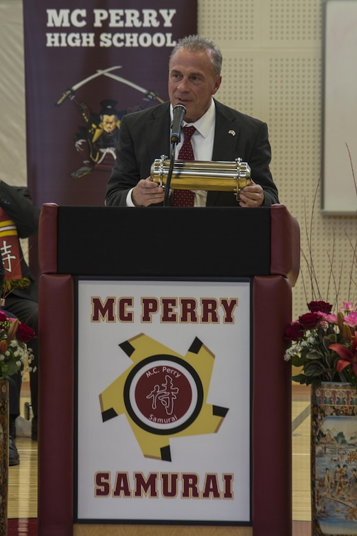 Jeffrey Carr, assistant principal of Matthew C. Perry High School, holds a time capsule while speaking to students and guests during the M.C. Perry High School ribbon-cutting ceremony at Marine Corps Air Station Iwakuni, Japan, Feb. 3, 2017. Construction of the new $67 million school began August 2014 and finished August 2016. The school includes a 400 meter track, artificial turf soccer and football field, a concession stand and 1,000 seat spectator grandstand. Replacing the old 38,000 square foot high school built in 1986 and costing approximately $3 million, the new high school provides improved security, resources and opportunities for students and staff. (U.S. Marine Corps photo by Cpl. Aaron Henson)