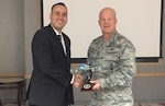 Gen. John W. Raymond, commander, Air Force Space Command, presents Maj. Francisco Leach an Air Force One model aircraft during the 2016 Advance Agent of the Year ceremony.