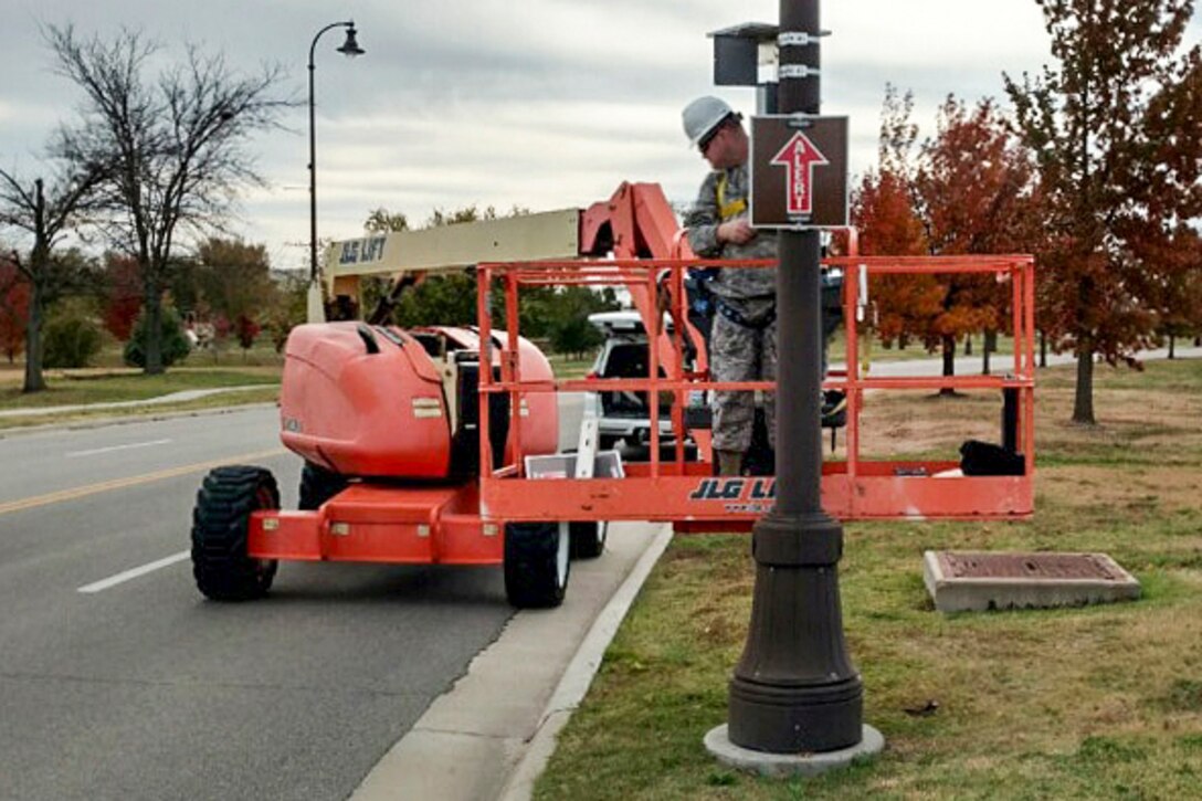 Air Force Tech. Sgt. Clayton Allen installs an alert route sign on a light pole, Nov. 17, 2016, at McConnell Air Force Base, Kan., Jan. 11, 2017. Allen and Air Force Master Sgt. Bartek Bachleda designed and built the signs, potentially saving the Air Force millions of dollars. Air Force photo by Master Sgt. Bartek Bachleda