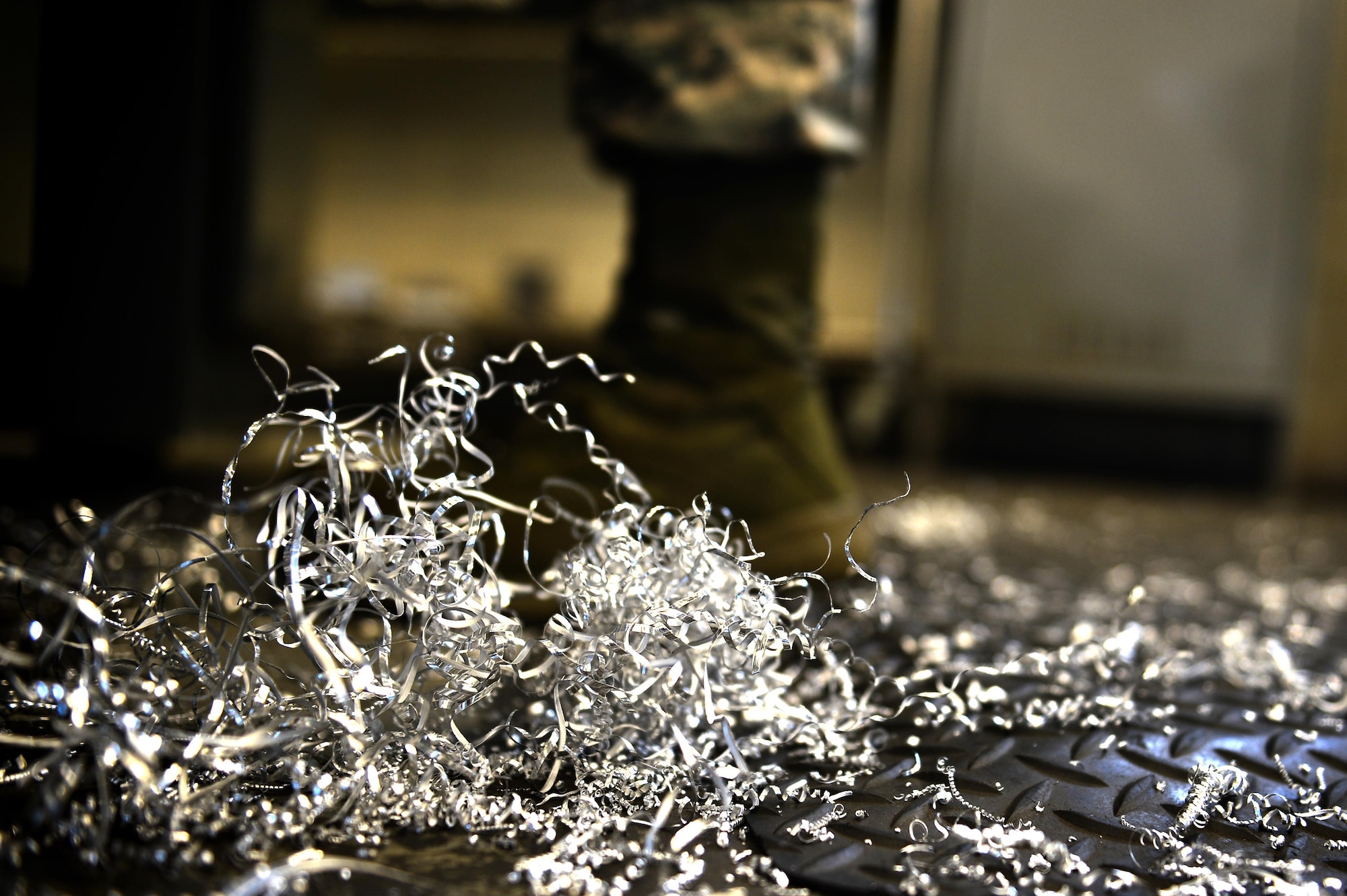 U.S. Air Force Airman 1st Class Mason Carny, 20th Equipment Maintenance Squadron aircraft metals technology technician, stands amongst metal shavings at Shaw Air Force Base, S.C., Jan. 31, 2017. Airmen assigned to the 20th EMS metals technology lab perform maintenance on various pieces of equipment around base ranging from F-16CM Fighting Falcon parts to munition accessories. (U.S. Air Force photo by Airman 1st Class Christopher Maldonado)