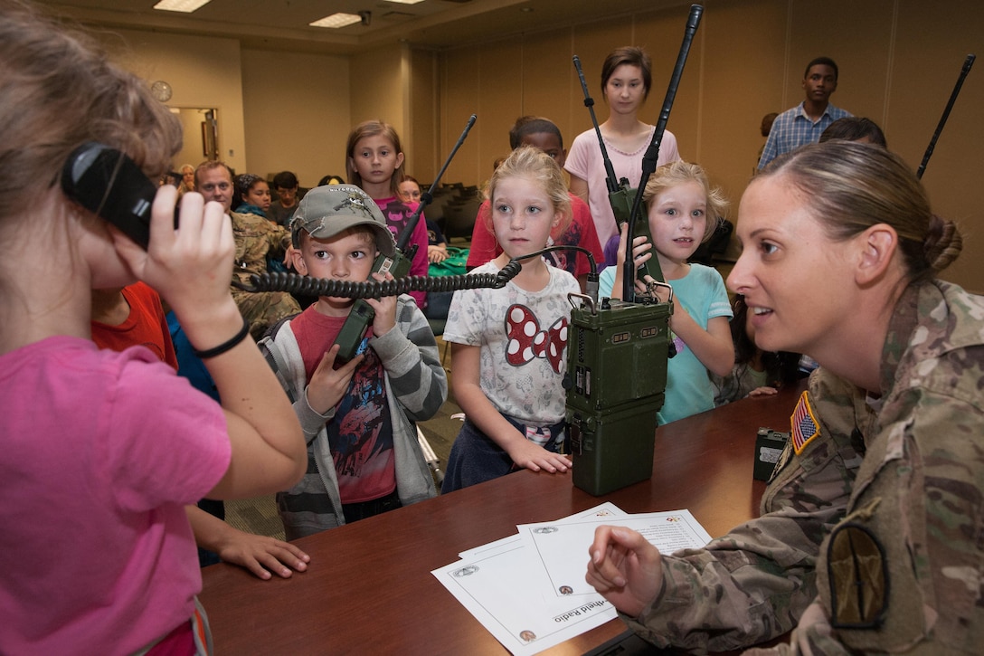 A member of U.S. Special Operations Command South listens as students use military radios during "Take Our Daughters and Sons to Work Day" at Homestead Air Reserve Base, Fla., Feb. 2, 2017. The command hosted the school event. Army photo by Staff Sgt. Osvaldo Equite