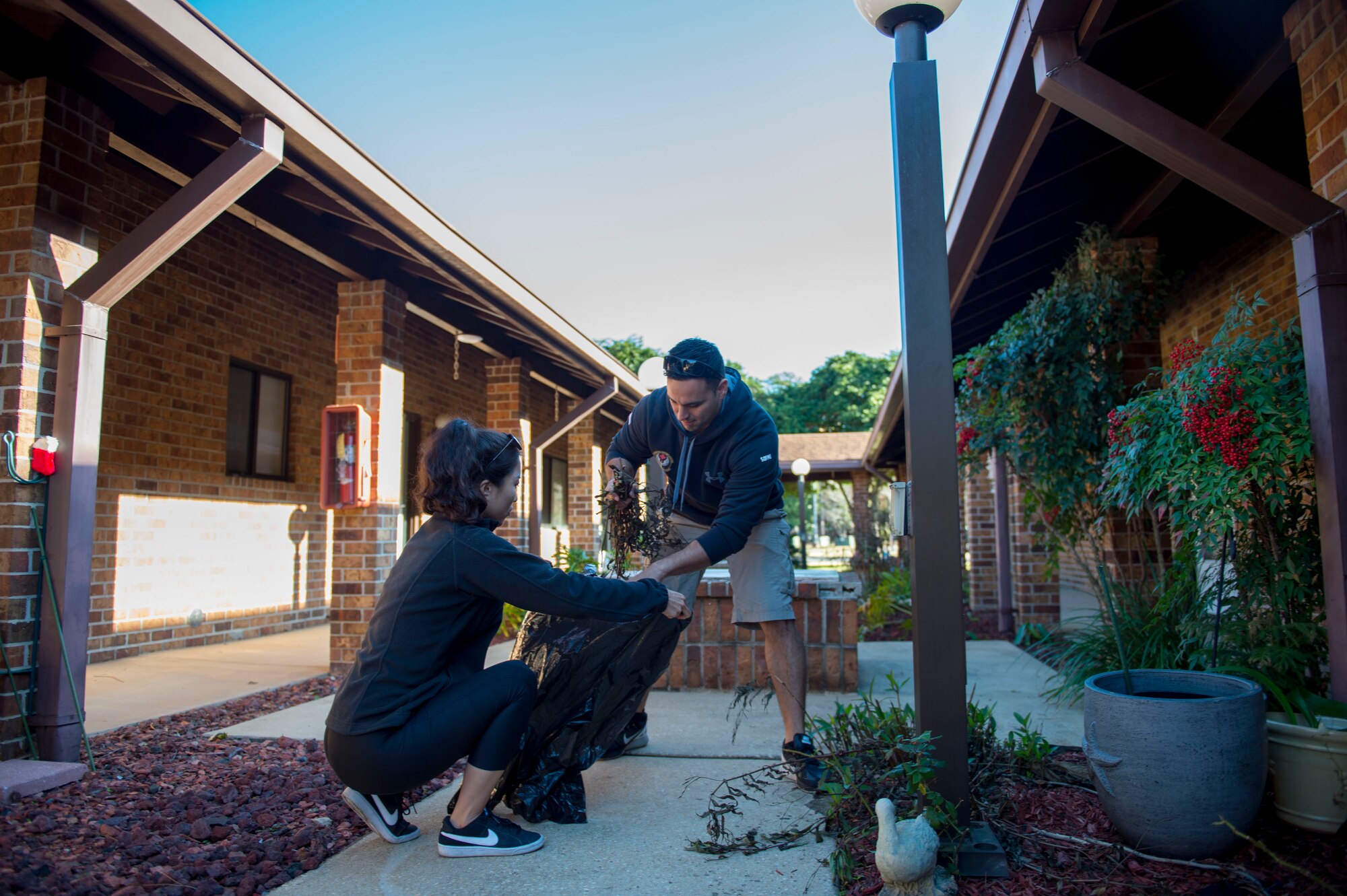 Tech. Sgt. Jose Rodriguez, an independent duty medical technician with the 1st Special Operations Support Squadron, right, and Huijeong Ha bag weeds for a resident at the Bob Hope Village in Shalimar, Fla., Feb. 2, 2017. Air Commandos volunteer at the Bob Hope village monthly to assist residents with minor maintenance issues and yard work. (U.S. Air Force photo by Senior Airman Krystal M. Garrett)
