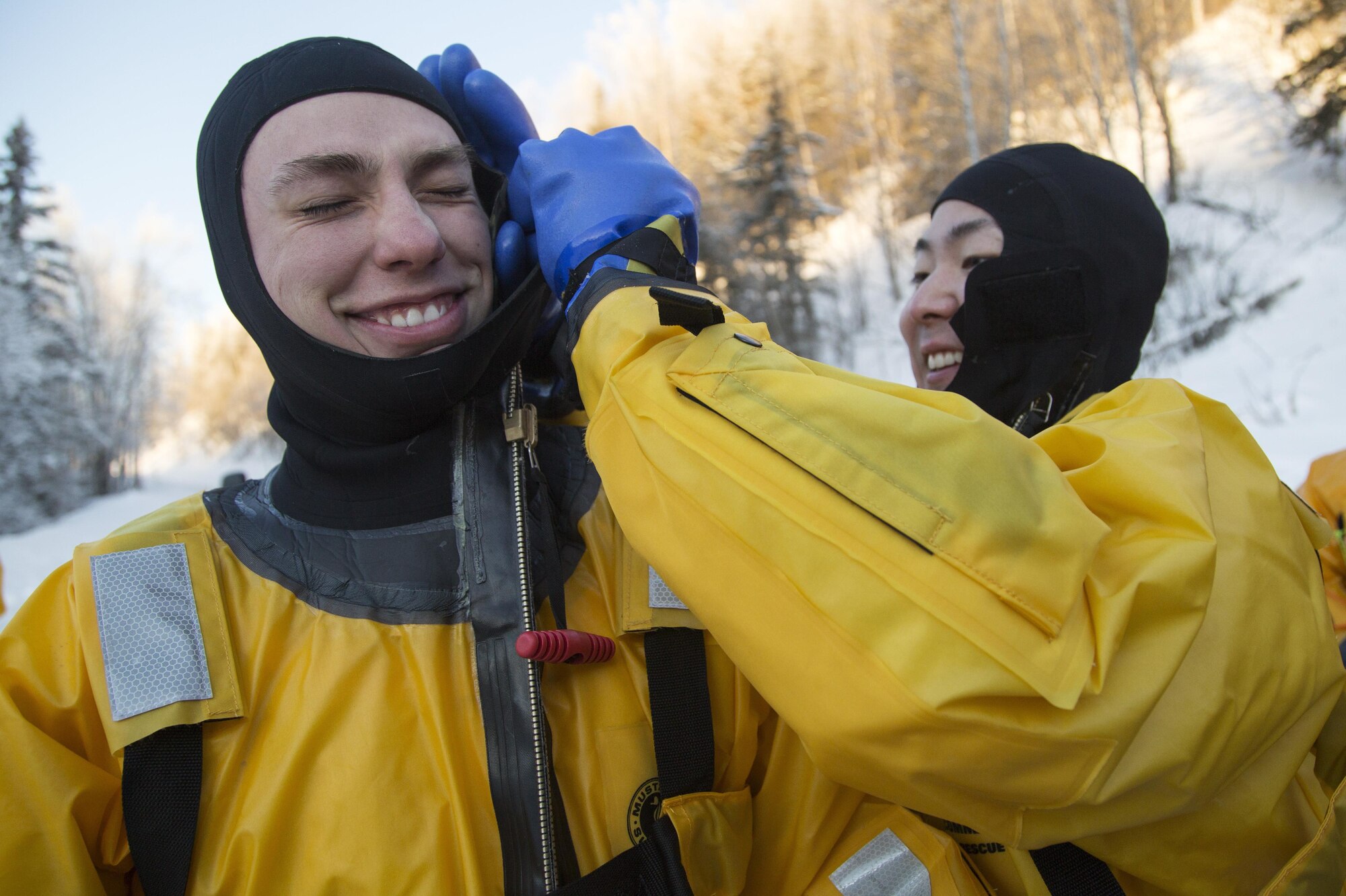 U.S. Air Force Senior Airman Joseph Pyun, right, assists Senior Airman Zachary Baldwin don a survival suit before conducting ice water rescue training at Joint Base Elmendorf-Richardson, Alaska Feb. 4, 2017. Pyun and Baldwin, natives of Cypress, Calif., and Alden, N.Y., respectively, are fire protection specialists assigned to the 673rd Civil Engineer Squadron. The training taught the JBER firefighters self-rescue techniques, victim recovery, and certified them as ice water rescue technicians. (U.S. Air Force photo/Alejandro Pena)