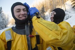 U.S. Air Force Senior Airman Joseph Pyun, right, assists Senior Airman Zachary Baldwin don a survival suit before conducting ice water rescue training at Joint Base Elmendorf-Richardson, Alaska Feb. 4, 2017. Pyun and Baldwin, natives of Cypress, Calif., and Alden, N.Y., respectively, are fire protection specialists assigned to the 673rd Civil Engineer Squadron. The training taught the JBER firefighters self-rescue techniques, victim recovery, and certified them as ice water rescue technicians. (U.S. Air Force photo/Alejandro Pena)