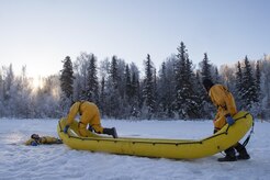 U.S. Air Force fire protection specialists, assigned to the 673rd Civil Engineer Squadron, use an inflatable raft to recover a simulated cold water victim while conducting ice water rescue training at Joint Base Elmendorf-Richardson, Alaska Feb. 4, 2017. The training taught the JBER firefighters self-rescue techniques, victim recovery, and certified them as ice water rescue technicians. (U.S. Air Force photo/Alejandro Pena)