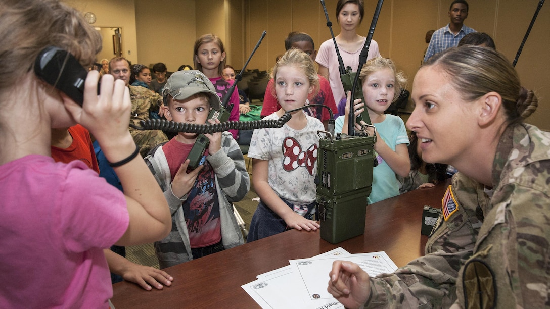 A member of U.S. Southern Command South listens as students use military radios during "Take Our Daughters and Sons to Work Day" at Homestead Air Reserve Base, Fla., Feb. 2, 2017. Army photo by Staff Sgt. Osvaldo Equite