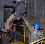 Staff Sgt. Joshua Spagnola of the New York National Guard’s 2nd Civil Support Team guides New York State Police Contaminated Crime Scene Emergency Response Team (CCSERT) member Investigator Brian Kenney  as he descends via a complex rope system during confined-space search-and-rescue training at the Watervliet Arsenal in Watervliet, N.Y. on Jan. 31, 2017.