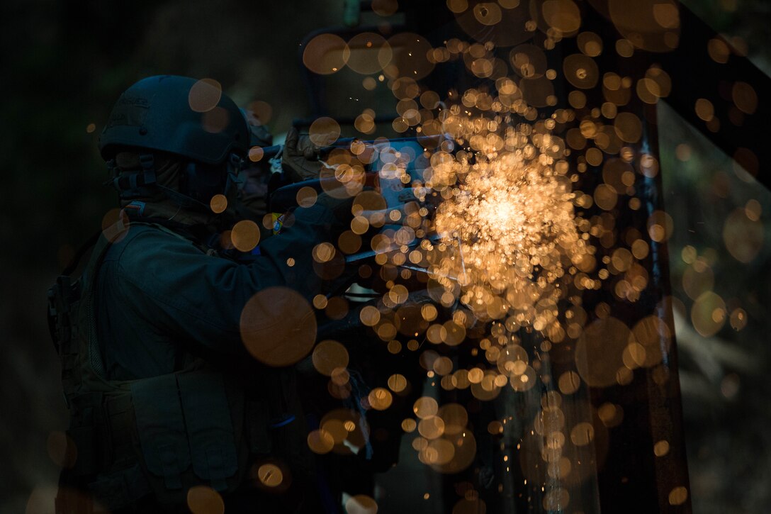 U.S. Marines attending the Methods of Entry (MOE) course, use a saw to cut through steel during a practical application exercise at Marine Corps Base Quantico, Va., Jan. 25, 2017. MOE teaches Marines advanced level skills on how to properly and effectively gain entry into buildings, structures and ships. 