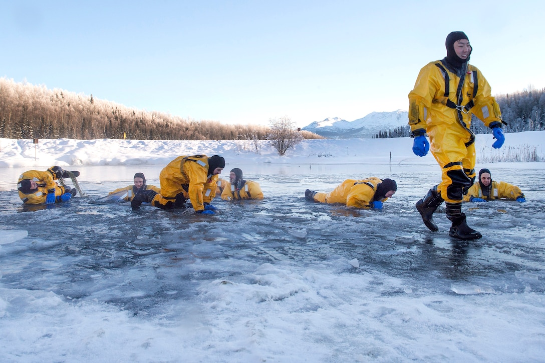 Air Force Senior Airman Joseph Pyun, right, and other fire protection specialists pull themselves from a frigid lake after conducting ice water rescue training at Joint Base Elmendorf-Richardson, Alaska, Feb. 4, 2017. Pyun is assigned to the 673rd Civil Engineer Squadron. Air Force photo by Alejandro Pena    