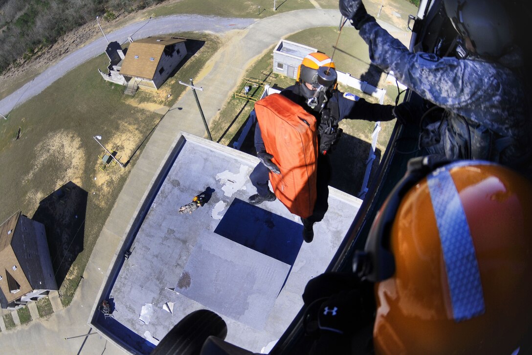 An Army National Guard crew chief assists an emergency first responder before being lowered from a UH-60 Black Hawk helicopter during Patriot South Exercise 2017 at the Gulfport and Port Bienville Industrial Complex, Mississippi, Jan. 31, 2017. Army National Guard photo by Staff Sgt. Roberto Di Giovine