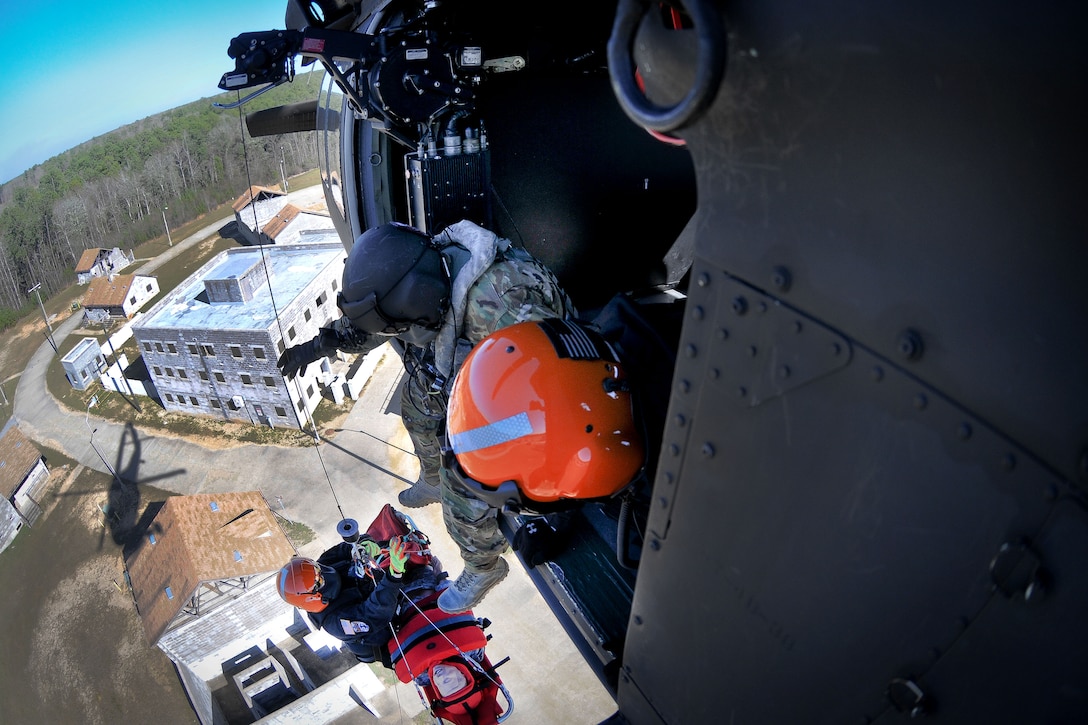 An Army National Guard crew chief hoists an emergency first responder and a mock casualty toward a UH-60 Black Hawk helicopter during Patriot South Exercise 2017 at the Gulfport and Port Bienville Industrial Complex, Mississippi, Jan. 31, 2017. Army National Guard photo by Staff Sgt. Roberto Di Giovine