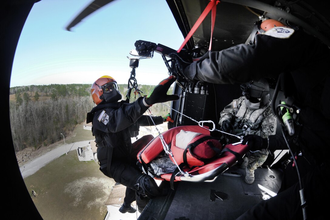 An Army National Guard crew chief hoists an emergency first responder and a mock casualty into a UH-60 Black Hawk helicopter during Patriot South Exercise 2017 at the Gulfport and Port Bienville Industrial Complex, Mississippi, Jan. 31, 2017. Army National Guard photo by Staff Sgt. Roberto Di Giovine