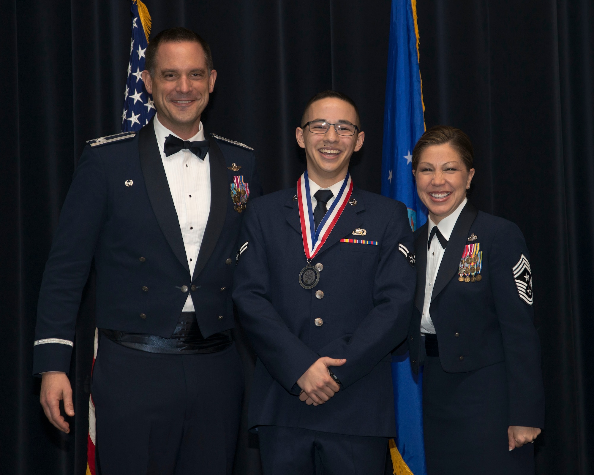 Col. Ethan C. Griffin, 436th Airlift Wing commander,  and Chief Master Sgt. Sarah Sparks, 436th AW command chief,  poses with Airman 1st Class Justin Schindlbeck, 436th Comptroller Squadron financial services technician, at the 2016 436th AW Annual Awards Ceremony Feb. 3, 2017, at the Rollins Center inside of Dover Downs, Dover, Del. Before the start of the event, nominees in each of the 14 categories were called to the stage to be recognized for their hard work. Individual categories nominees received medallions. (U.S. Air Force photo by Staff Sgt. Jared Duhon)