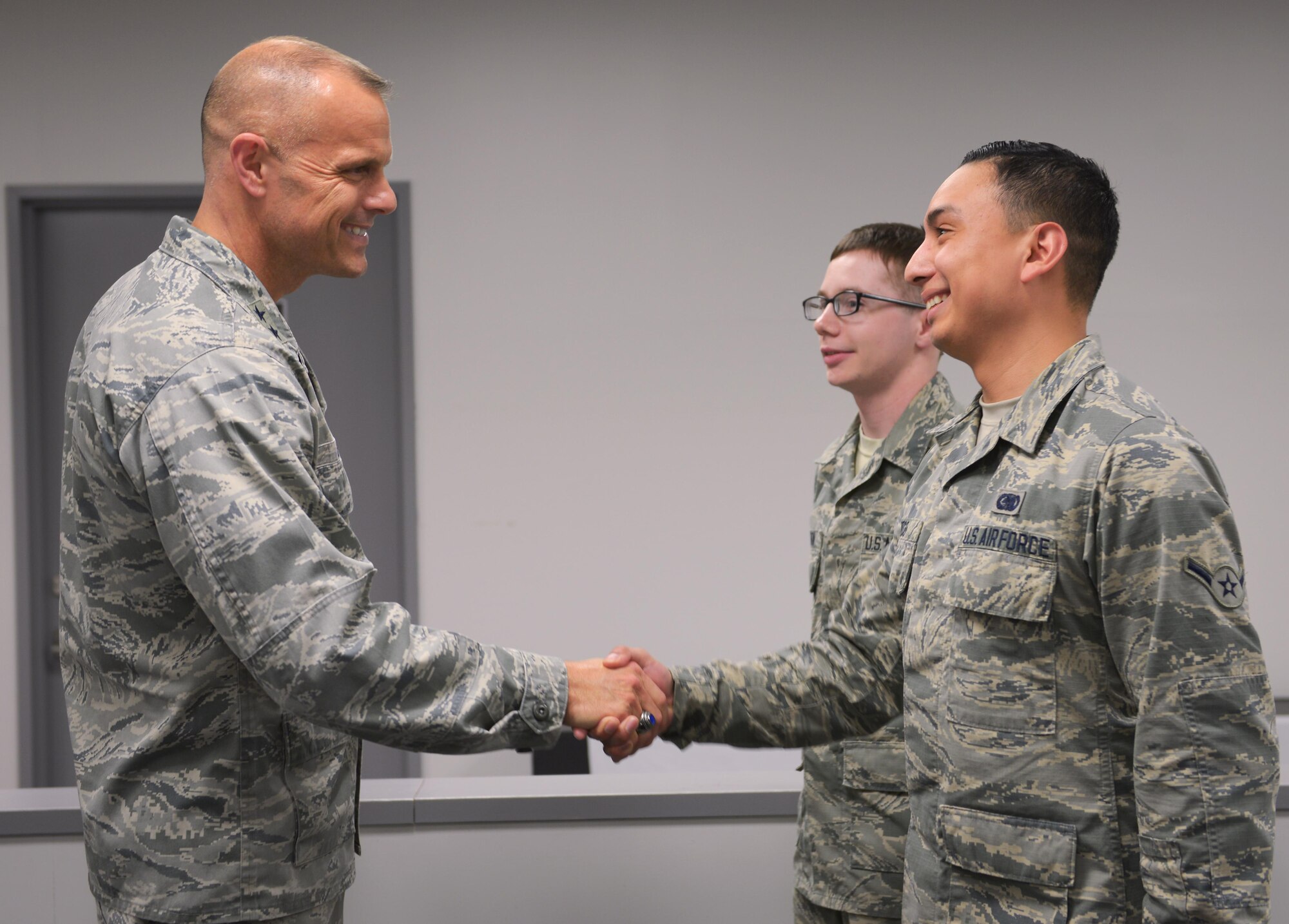 Maj. Gen. Bradley Spacy, Air Force Installation and Mission Support Center commander, coins two members of the 374th Logistics Readiness Squadron at Yokota Air Base, Japan, Jan. 30, 2017. Spacy visited three Pacific Air Forces bases to see the installation and mission support operations across the board. (U.S. Air Force photo by Senior Airman Elizabeth Baker)