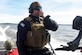 U.S. Coast Guard Maritime Enforcement Specialist 1st Class Corey Philips, Port Security Unit 305 tactical crewmember and engineer, talks with another USCG boat crew during a deployment exercise at Joint Base Langley-Eustis, Va., Feb. 2, 2017. The boat crews performed maritime tactics to deter the acting opposing force from reaching land. (U.S. Air Force photo by Airman 1st Class Derek Seifert)