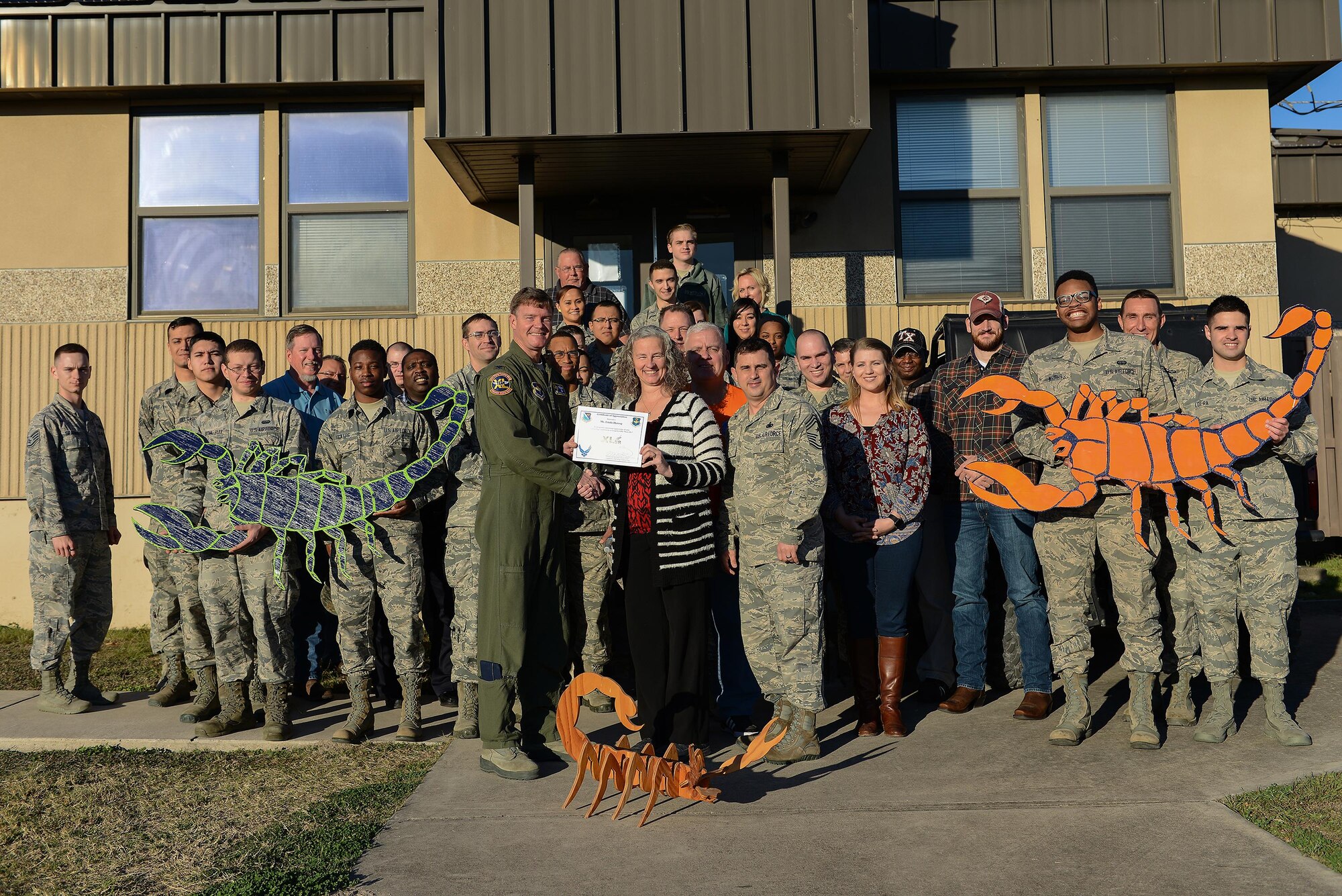 Linda Herzog, 47th Communications Squadron wing information systems security manager (front center), accepts the “XLer of the Week” award from Col. Thomas Shank, 47th Flying Training Wing commander (front left), and Chief Master Sgt. George Richey, 47th FTW command chief (front right), on Laughlin Air Force Base, Texas, Jan. 25, 2017. The XLer is a weekly award chosen by wing leadership and is presented to those who consistently make outstanding contributions to their unit and Laughlin. (U.S. Air Force photo/Airman 1st Class Benjamin N. Valmoja)