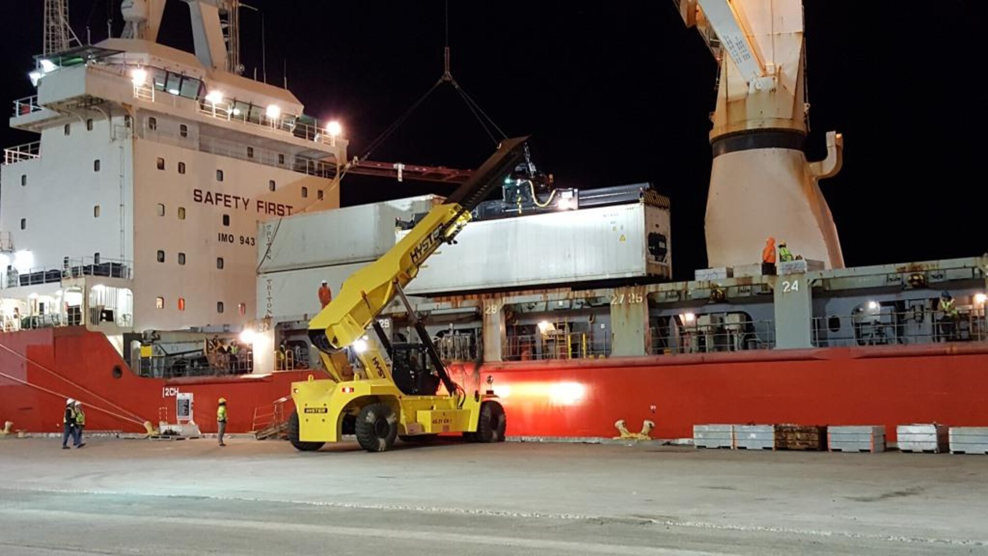 A reach stacker is used to load cargo containers onto the deck of the MV Ocean Giant.