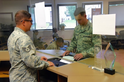 Air Force Staff Sgt. Kelly Querry, left, with the Ohio Air National Guard's 178th Wing Financial Management section, processes a payment voucher for a customer at Ramstein Air Base, Germany, in July 2016. Maintaining strong financial health is important for National Guard members to remain mission ready, said Guard officials. For those who may need financial planning assistance, a variety of resources are available at many military installations. 