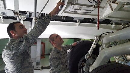U.S. Air Force Capt. Sean Cox, (right), 437th Aircraft Maintenance Unit officer in charge, and Staff Sgt. Dustin Wineinger, (left), 373rd Training Squadron Detachment 5 aeronautical repair instructor, inspect a landing gear training assembly. Cox was one of 15 Air Force officers selected to attend the inaugural Advanced Sortie Production Course at the Advanced Maintenance and Munitions Operations Schoolhouse at Nellis Air Force Base, Nevada, Dec. 7, 2016.
