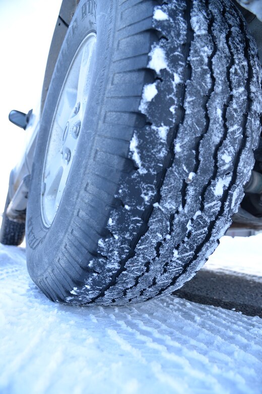 An icy vehicle tire is shown on top of a layer of ice during the winter months Feb. 8, 2017, at Malmstrom Air Force Base, Mont. To be safe driving during hazardous road conditions, the American Automobile Association suggests watching weather reports prior to leaving for a destination. AAA also suggests not using cruise control, increasing the normal dry pavement following distance from 3-4 seconds to 8-10 seconds, slowing down when visibility is low and accelerating and decelerating slowly. (U.S. Air Force photo/Airman 1st Class Daniel Brosam)