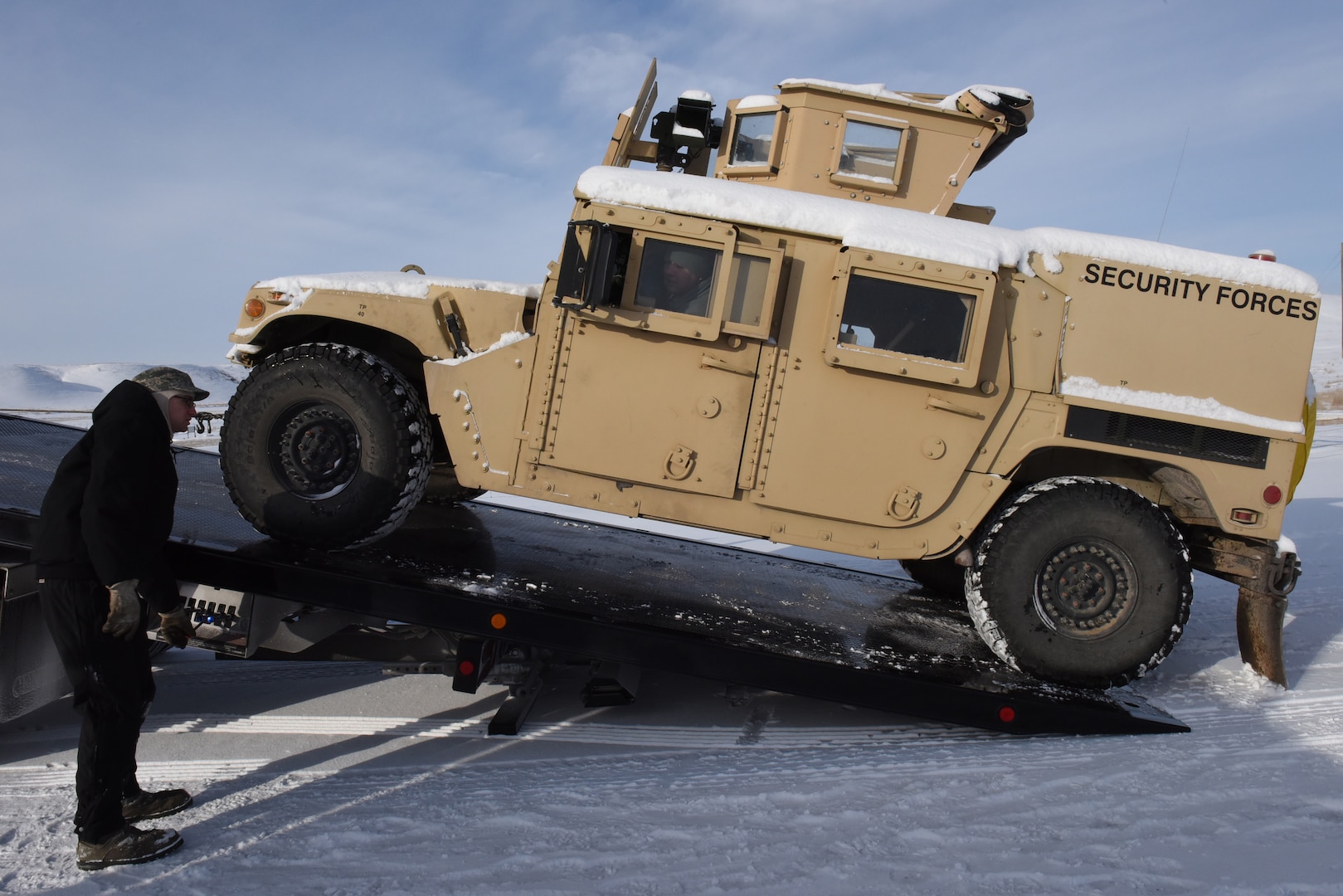 Senior Airman Ian Lauzon, 341st Logistics Readiness Squadron vehicle operator, activates a pulley as he moves a Humvee onto the back of a tow truck at a missile alert facility Feb. 7, 2017.  The Humvee will be transferred to Malmstrom Air Force Base, Mont., for maintenance.  (U.S. Air Force photo/Jason Heavner)