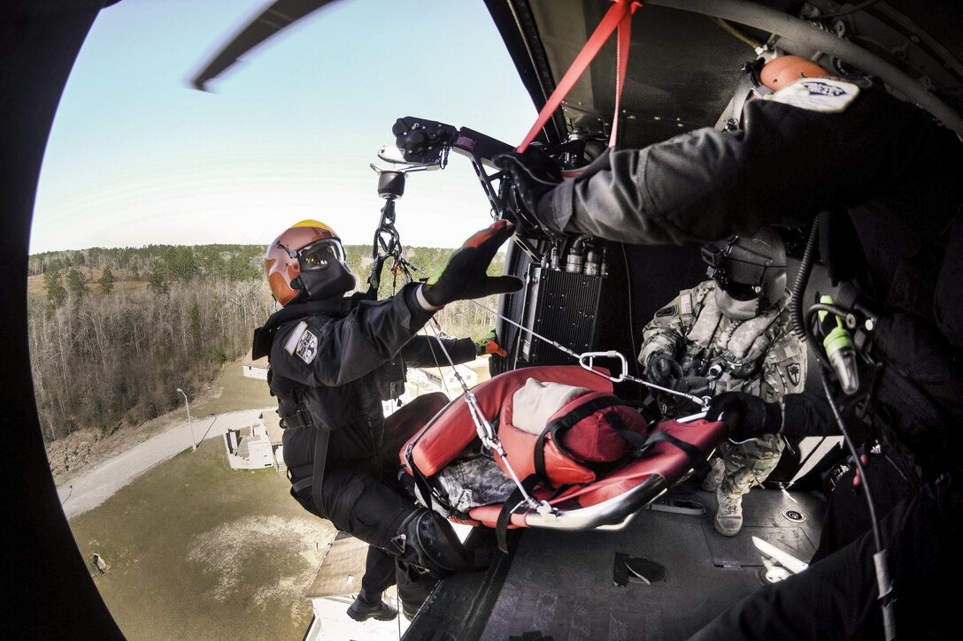 A soldier assists an emergency first responder and a mock casualty onto a UH-60 Black Hawk helicopter during Patriot South Exercise 2017 at Port Bienville Industrial Complex in Gulfport, Miss., Jan. 31, 2017. The soldier is a crew chief assigned to the South Carolina National Guard. Army National Guard photo by Staff Sgt. Roberto Di Giovine