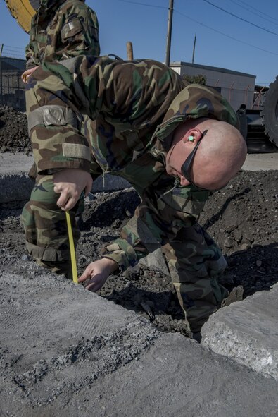 An Airman with the 374th Civil Engineering Squadron measures a hole’s depth during a Rapid Airfield Damage Repair exercise Feb. 8, 2017, at Yokota Air Base, Japan. RADR is a modern airfield repair process to efficiently fix a runway in the event of an incident. (U.S. Air Force photo by Airman 1st Class Donald Hudson)
