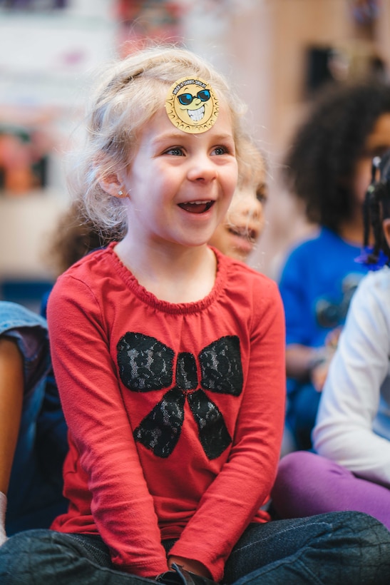 A child smiles while listening to a story told by Airman 1st Class Mckaylah Cumlin, 779th Dental Squadron dental assistant, at the Child Development Center at Joint Base Andrews, Md., Feb. 3, 2017. In celebration of National Children's Dental Health Month, members from the 779th DS visited children for dental health class to increase their awareness of good oral health habits. (U.S. Air Force photo by Senior Airman Delano Scott)