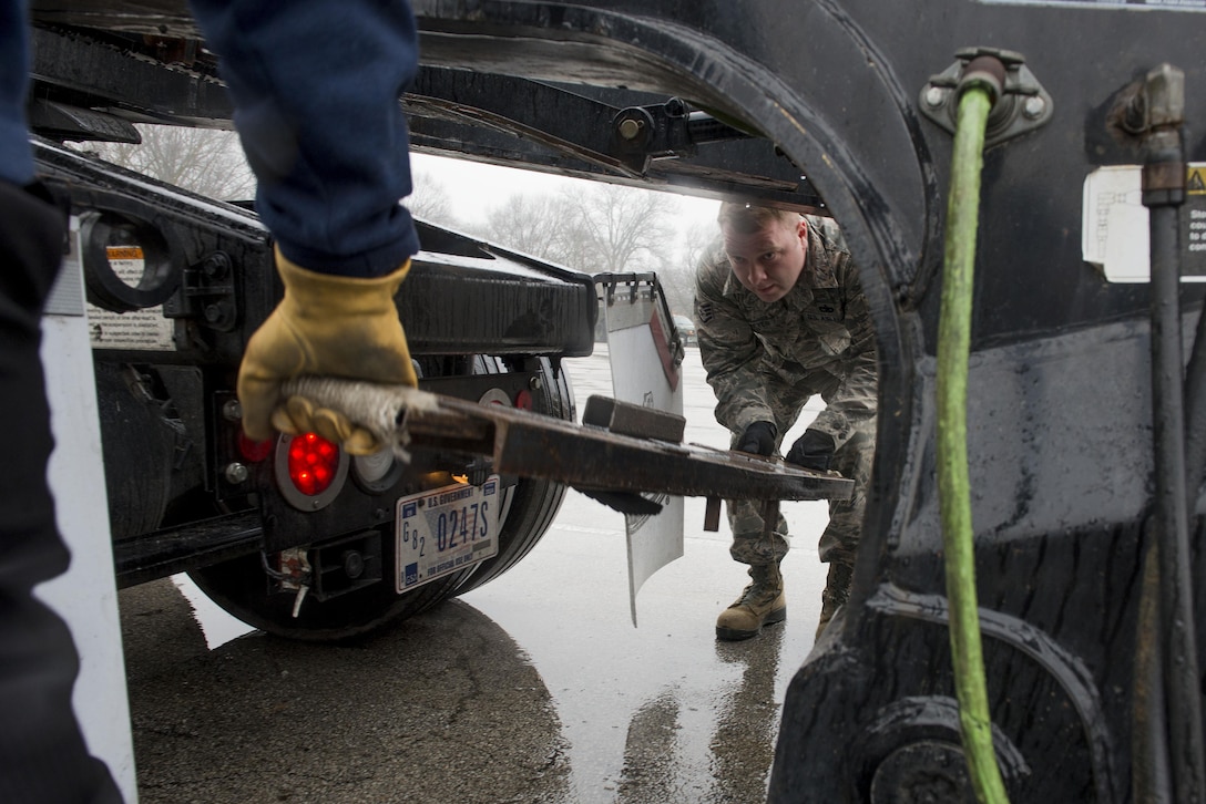 Air Force Staff Sgt. Joshua Meyer, 375th Logistics Readiness Squadron vehicle operations control center noncommissioned officer in charge, lifts the Meyer’s Bar onto the hitch of the lowboy at Scott Air Force Base, Ill., Jan. 19, 2017. The Meyers Bar supports a lowboy trailer’s hydraulic gooseneck hitch to prevent it from bending. Air Force photo by Senior Airman Joshua Eikren