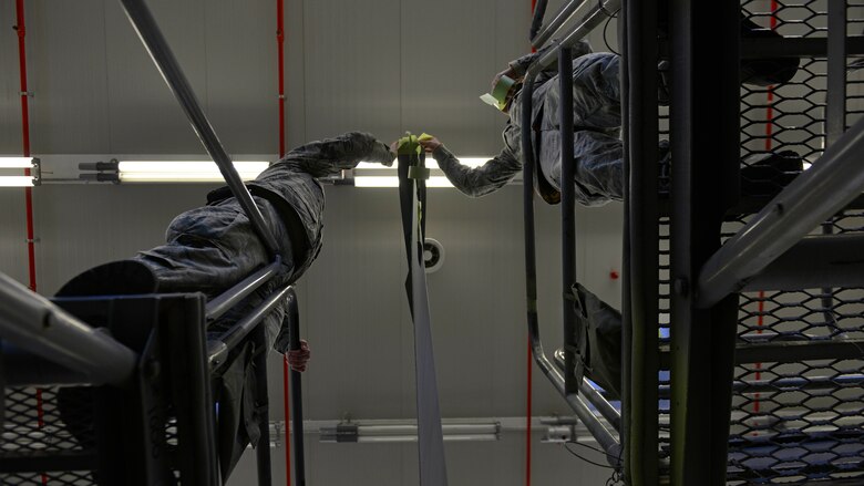 Senior Airman Adam Ciecalone, 31st Maintenance Squadron Aircraft Structural Maintenance journeyman, and Staff Sgt. Stephen Ramsbacher, 31st Maintenance Squadron Aircraft Structural Maintenance craftsman, tape off areas on an F-16 Fighting Falcon tail before sanding it at Aviano Air Base, Italy, Jan. 23, 2017. Ciecalone and Ramsbacher taped areas that didn’t need to be sanded. (U.S. Air Force photo by Senior Airman Cary Smith)