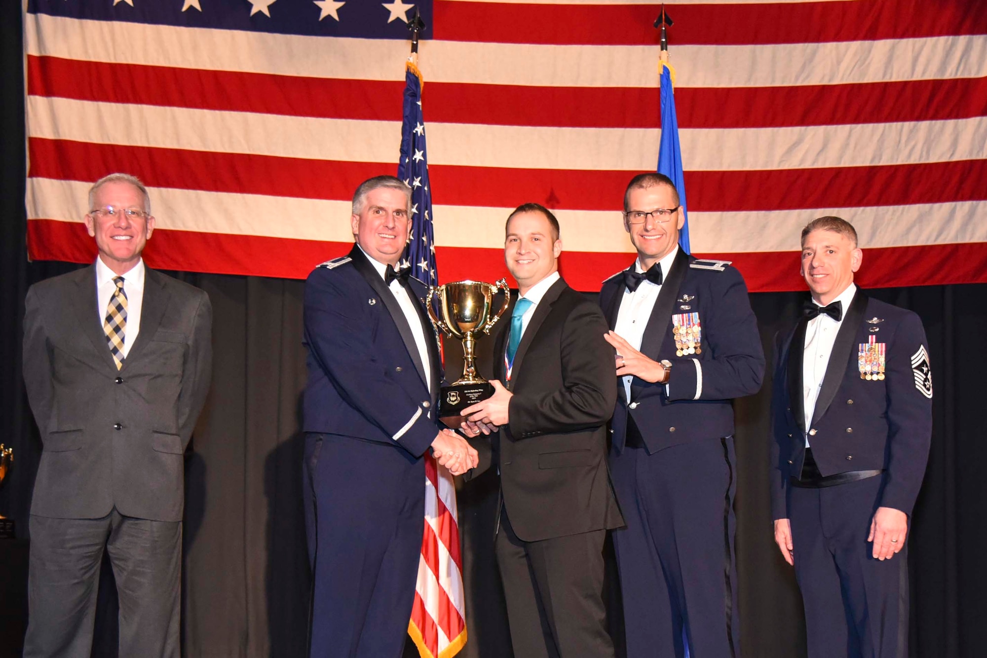 Ryan H. Lee, 22nd Security Forces Squadron, center, accepts the 2016 Civilian Category I of the Year award, Feb. 3, 2017, at McConnell Air Force Base, Kan. The annual awards ceremony recognized military and civilian members who excel in their areas of responsibilities, leadership qualities, community involvement, self-improvement and innovation from of January to December 2016. (U.S. Air Force photo/Senior Airman Christopher Thornbury)