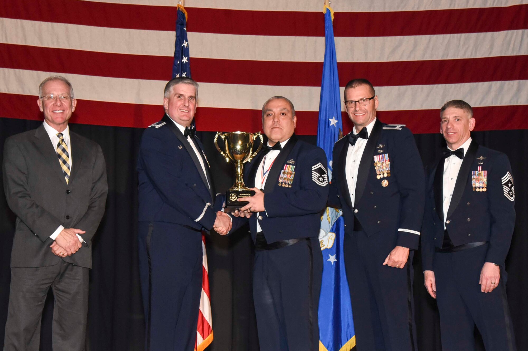 Senior Master Sgt. Gregory D. Bishop, 22nd Security Forces Squadron, center, accepts the 2016 Senior Noncommissioned Officer of the Year award, Feb. 3, 2017, at McConnell Air Force Base, Kan. The annual awards ceremony recognized military and civilian members who excel in their areas of responsibilities, leadership qualities, community involvement, self-improvement and innovation from January to December 2016. (U.S. Air Force photo/Senior Airman Christopher Thornbury)